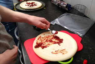 Adding tomato topping to a pizza