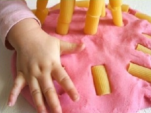 Toddler hands in pink play doh with pasta tubes - homemade toys