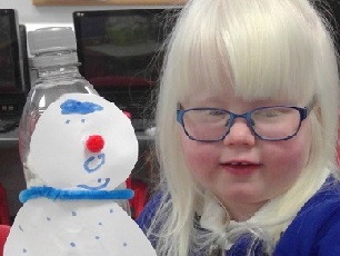 Girl with blonde hair wearing glasses with a paper snowman